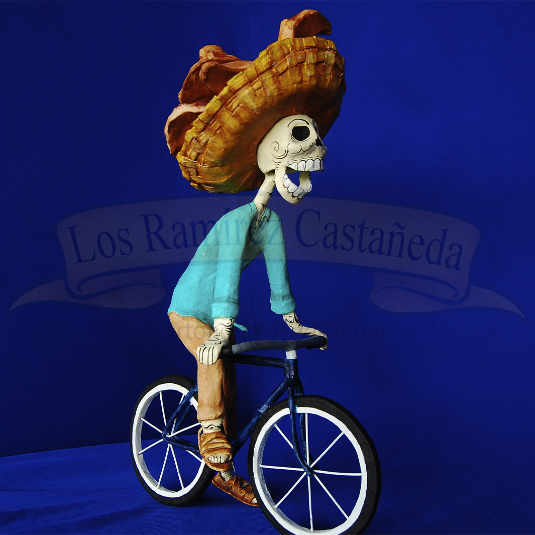 personaje en calaca de panadero con canasto de pan montado en una bicicleta